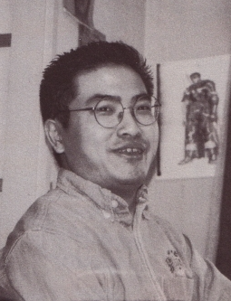 Kentaro Miura shot in black and white. Behind him on a wall is an illustration of Guts.